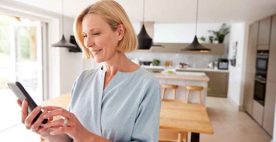 Resident holding a mobile device in a modern home